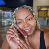 Model wearing Berry vegan lip gloss with high-shine, non-sticky finish designed to complement melanin-rich skin tones.