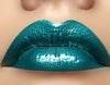 Swatch of Emerald City Lip Gloss on lips; a stunning green shimmering lip gloss.