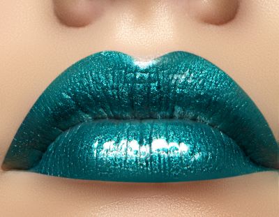 Green Metallic Emerald City Lip Gloss swatch showing turquoise green shade over lipstick for bold makeup lovers.
