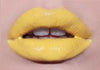 Lip swatch showing bold yellow liquid lipstick over matte yellow lipstick for editorial makeup look.